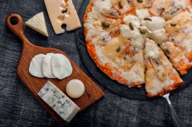 Farklı türde bir taş ve bir siyah çizik tebeşir tahtası üzerinde peynir İtalyan pizza. Geleneksel İtalyan yemekleri. Üstten görünüm.
