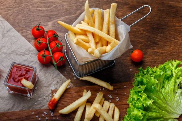 Ketçap, salata ve domates ahşap kahverengi masa üzerinde bir kılavuzda patates kızartması. Üstten görünüm.