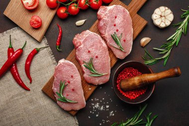 Çiğ domuz biftek domates, biberiye, sarımsak, biber, tuz ve baharat harç paslı kahverengi zemin üzerine ile kesme tahtası üzerinde parçaları. Üstten görünüm.