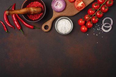 Çiğ domuz biftek domates, biberiye, sarımsak, kırmızı biber, defne yaprağı, soğan, tuz ve baharat harç paslı kahverengi zemin üzerine ile kesme tahtası üzerinde parçaları. Metin alanı olan üstten görünüm.