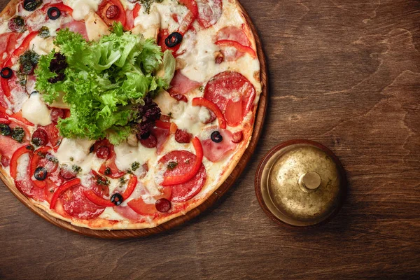 Pizza jambon, salam, peynir, mantar, domates, biber ve salata ahşap kahverengi tahtası, üstten görünüm.