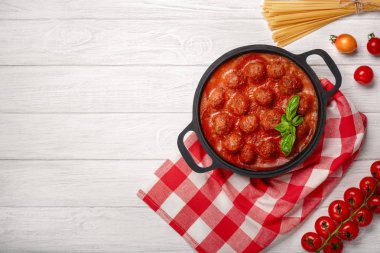 Köfte domates sosu ile baharat ve fesleğen bir kızartma tavası ve kiraz domates Beyaz ahşap tahta üzerinde içinde. Üstten görünüm.
