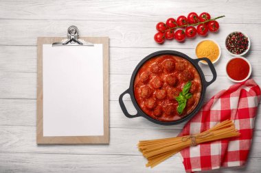Köfte domates sosu ile baharat ve fesleğen bir kızartma tavası ve kiraz domates Beyaz ahşap tahta üzerinde içinde. Metin alanı olan üstten görünüm.