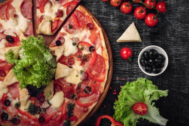 Pizza jambon, salam, peynir, mantar, domates, biber ve salata siyah tebeşir tahtası, üstten görünüm.