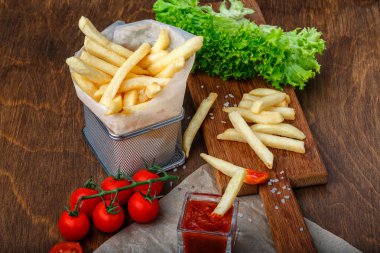 Ketçap, salata ve domates ahşap kahverengi masa üzerinde bir kılavuzda patates kızartması. Üstten görünüm.