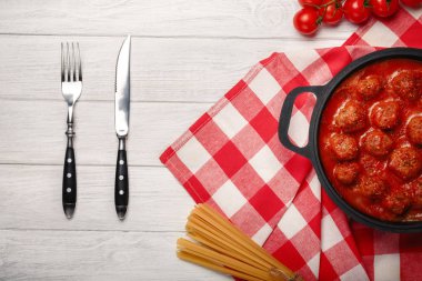 Baharat beyaz ahşap tahta üzerinde bir tavada domates soslu levrek. Üstten görünüm.