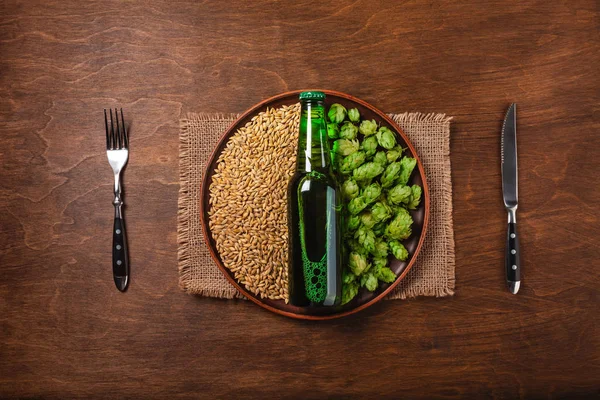 Бутылка Пива Зеленом Свежем Хмеле Пшеничное Зерно Ножом Вилкой Тарелке — стоковое фото