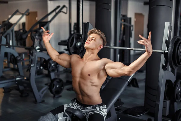 暗い背景にジムで体重を持ち上げる筋肉の若い男のクローズアップ — ストック写真