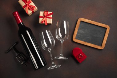 Bir şişe şarap ve bir bardak ve bir nişan yüzüğü ile Sevgililer günü. Kopya alanı ile üstten görünüm.