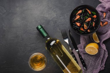 Modern İtalyan yemeği, Akdeniz yemekleri, deniz ürünleri, zeytinyağı ve fesleğen, karanlık paslı tablo ile siyah mürekkep balığı mürekkep spagetti makarna. Beyaz kopya alanı üstten görünüm üzerinde şarap