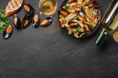 Spagetti vongole, istiridye ve midye otlar ile plaka ile İtalyan Deniz ürünleri makarna ve rustik taş zemin üzerine beyaz şarap. Geleneksel İtalyan Deniz mutfağı, yakın çekim, üstten görünüm.