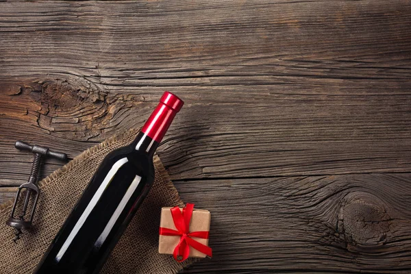 Holiday Dinner setting with red wine and gift on rustic wood in flat lay view