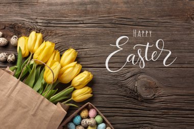 Sarı laleler bir kağıt torba, bir ahşap arka plan üzerinde bir yuva ile Paskalya yumurta. Kopya alanı ile üstten görünüm