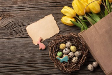 Paskalya gingerbread çerezleri ahşap masa ve sarı laleler. Tebrik kartı. Kopya alanı ile üstten görünüm