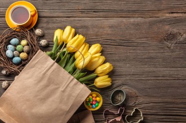 Paskalya gingerbread çerezleri ahşap masa ve sarı laleler. Tebrik kartı. Kopya alanı ile üstten görünüm.
