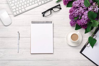 Office Masaüstü leylak, kahve fincanı, klavye, defter ve kalem beyaz tahtalar üzerinde bir buket. Metniniz için yer ile Üstten Görünüm.