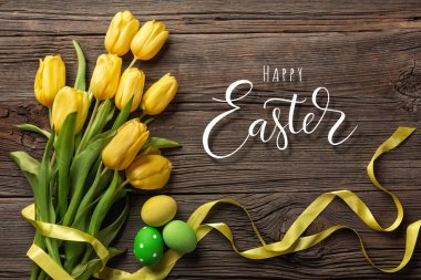 Sarı laleler bir kağıt torba, bir ahşap arka plan üzerinde bir yuva ile Paskalya yumurta. Kopya alanı ile üstten görünüm.