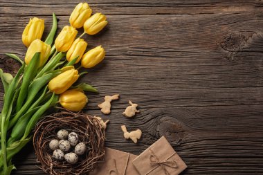 Paskalya renkli yumurta ve ahşap masa üzerinde Sarı laleler arka plan. Kopya alanı ile Üstten Görünüm