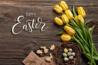 Paskalya renkli yumurta ve ahşap masa üzerinde Sarı laleler arka plan. Kopya alanı ile Üstten Görünüm