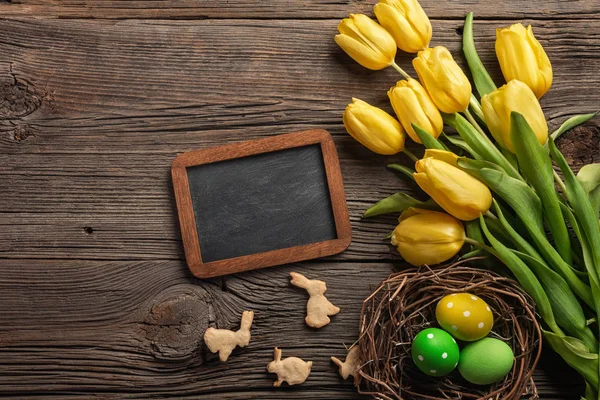 Paskalya renkli yumurta ve ahşap masa üzerinde Sarı laleler arka plan. Kopya alanı ile Üstten Görünüm