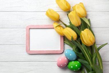 Lale çiçek buketi ve Paskalya yumurta Paskalya tebrik kartı. Selam yeri olan beyaz ahşap masa üzerinde Üstten Görünüm