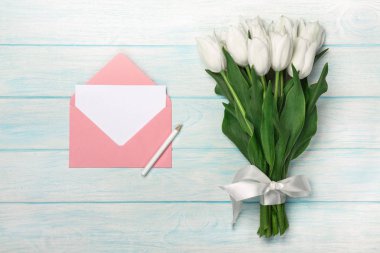 Bir buket sevgi Not ve renk zarf mavi ahşap kurullarında ile beyaz laleler