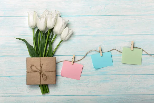 Beyaz Laleler ve zarf ip ve mavi ahşap kurullarında clothespins ile renk sopa ile bir buket