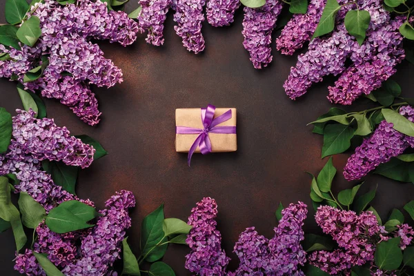 A bouquet of lilacs with gift box on rusty background