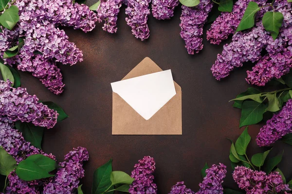 A bouquet of lilacs with craft envelope, a love note on rusty background
