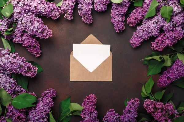 A bouquet of lilacs with craft envelope, a love note on rusty background