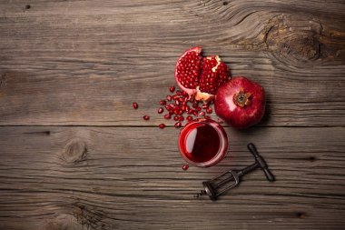 Olgun nar meyve ile bir kadeh şarap ve bir tirbuşon ahşap arka plan üzerinde