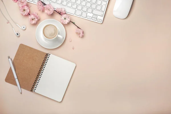 Kapuçino, sakura çiçekler, klavye, çalar saat, defter pastel pembe arka plan üzerinde beyaz Kupası
