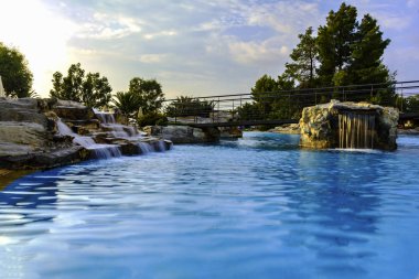 Resort, Yüzme Havuzu ile Yunanistan beldesinde mavi su temizleyin. Yapay şelaleler benzersiz, kendine özgü bir manzara oluşturun. Ağaçlar ve çalılar etrafında büyümek.