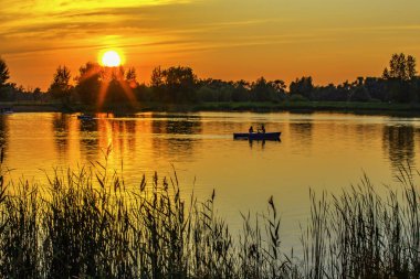 Parlak akşam gün batımı. Gölde bir teknede Aşıklar.