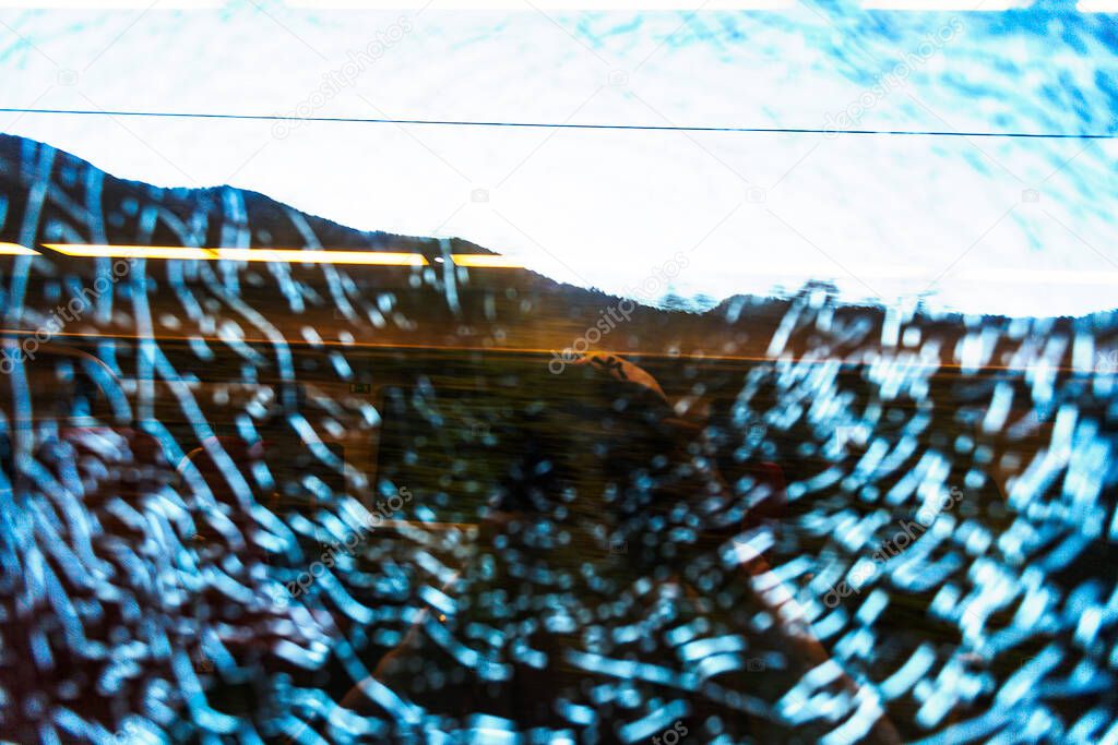 reflections in a broken window of an electric train change depending on the lighting and landscape outside the window