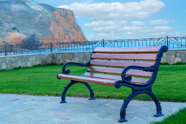 Sonbahar mavi gökyüzünün arka planında, beyaz bulutlar ve kara deniz dalgalarıyla bankta.