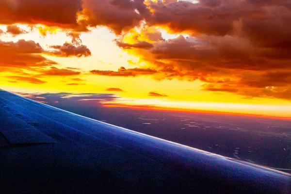 Under the wing of the plane, white fluffy and dark gloomy clouds float by, changing their color from the desire of the sun