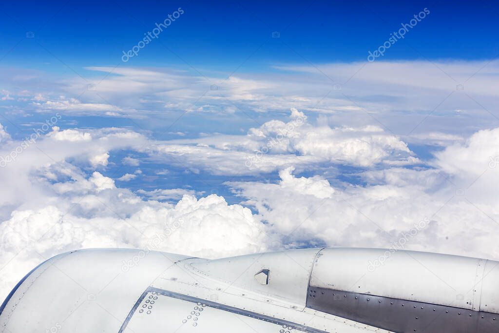 Under the wing of the plane, white fluffy and dark gloomy clouds float by, changing their color from the desire of the sun
