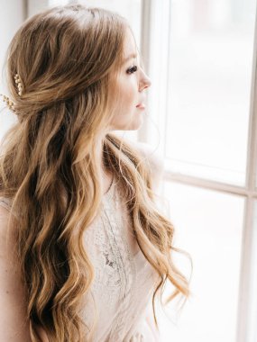 Genç ve güzel gelini güzel saç modeli ve penceresine bakarak makyaj ile portresi