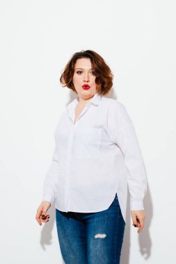 Artı boyutu kadın kameraya bakarak ve hava beyaz arka plan üzerinde dururken, üfleme şık kıyafeti çekici