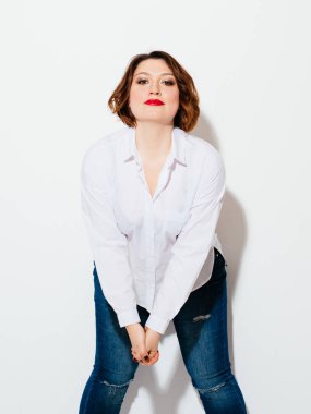 Öne eğilerek ve beyaz arka plan üzerinde dururken kamera bakıyor güzel artı boyutu Bayan