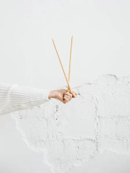 Closeup image of female hand with big wooden knitting needles