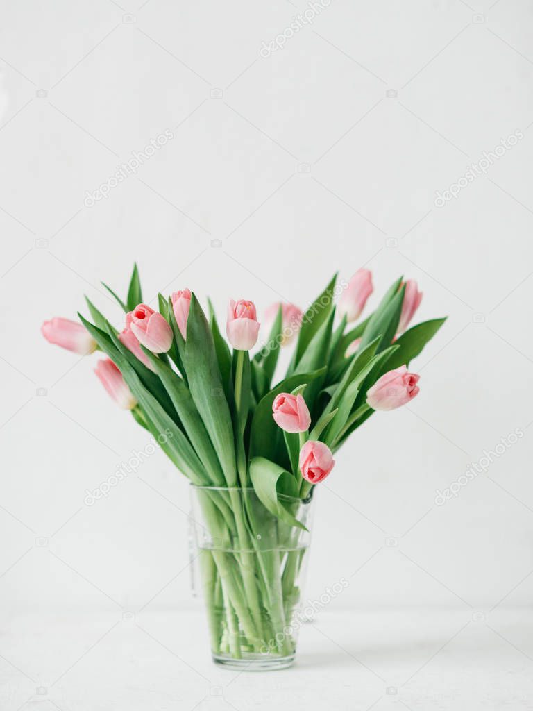 Tulip flowers bouquet on white table against white wall with day light. Mothers day celebration concept