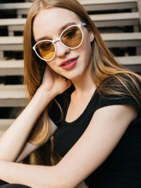 Siyah aşınma ve güneş gözlüğü uzun sarı saçlı kentsel duvar boyunca yakın poz trendy rahat genç kadın portresi 