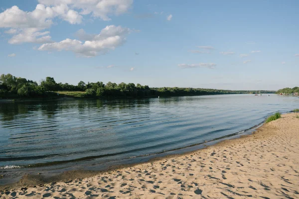 Sunny summer landscape with river, sandy beach and beautiful green trees on the river bank