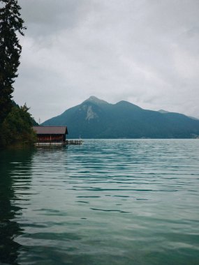 Lake Walchensee geleneksel ahşap tekne ev arasında dağlar bulutlu havalarda, Bavyera, Almanya 