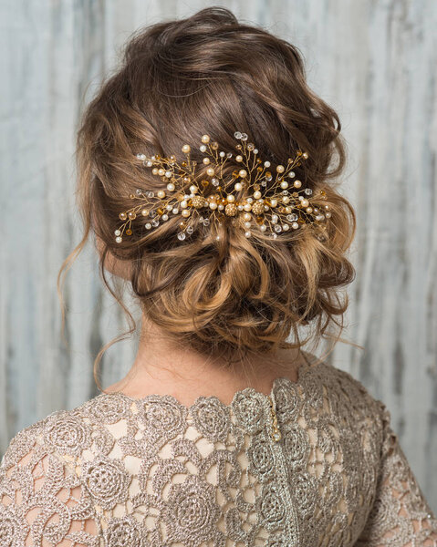 Close-up image of beautiful hairstyle decorated by gold beaded shiny hair accessory, rear view