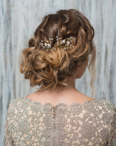 Woman with beautiful hairstyle decorated by fancy shiny hair accessory, rear view