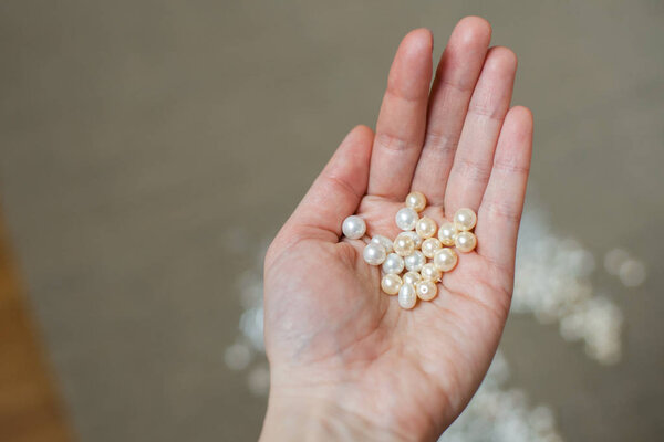 Close-up of female palm holding white and ivory freshwater pearls
