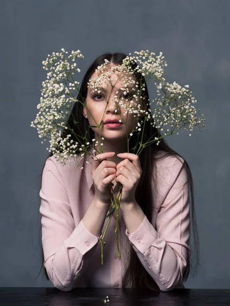 Mujer joven mirando a la cámara a través de flores — Foto de Stock